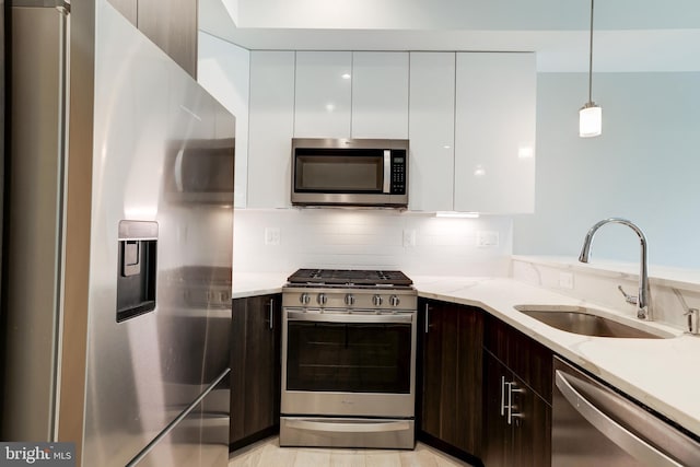 kitchen with pendant lighting, sink, white cabinetry, stainless steel appliances, and dark brown cabinets