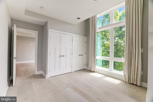 unfurnished bedroom featuring light hardwood / wood-style floors and multiple windows