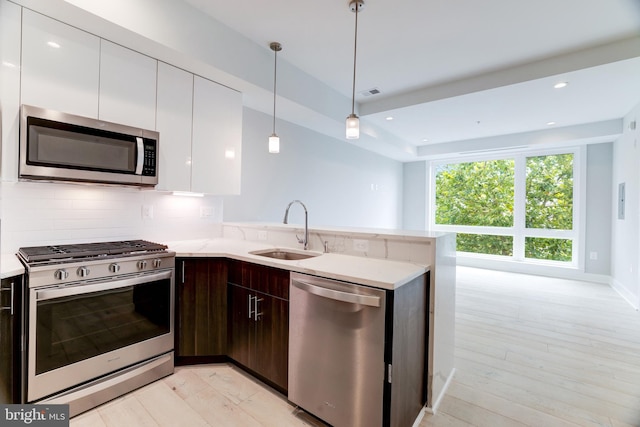 kitchen featuring stainless steel appliances, dark brown cabinets, hanging light fixtures, white cabinets, and sink