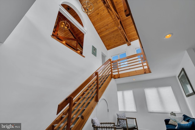 stairway with high vaulted ceiling, beamed ceiling, wood ceiling, and a notable chandelier