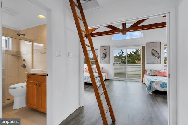 interior space featuring vaulted ceiling with beams, ensuite bathroom, and access to outside