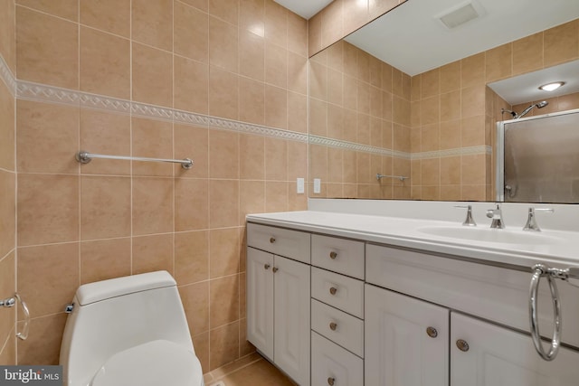 bathroom with vanity, toilet, a shower with shower door, and tile walls