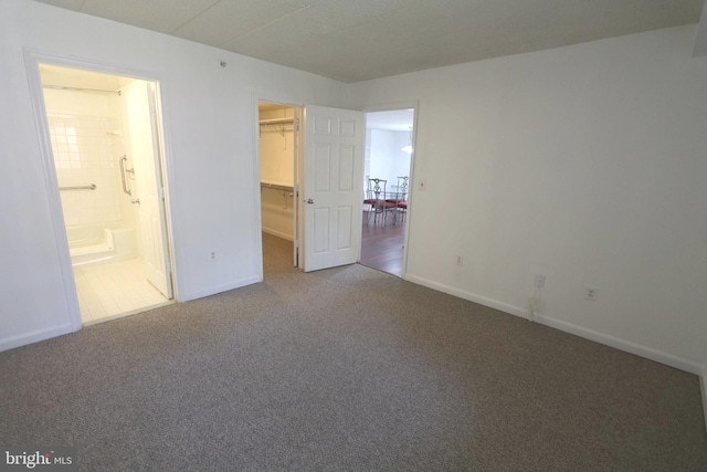 unfurnished bedroom featuring a walk in closet, carpet, connected bathroom, and a closet