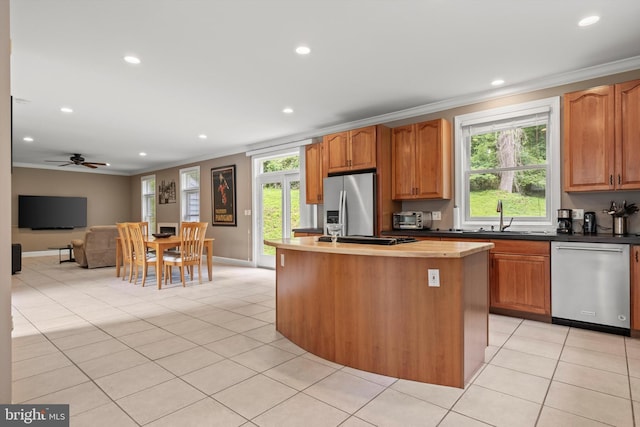 kitchen featuring ceiling fan, light tile patterned flooring, ornamental molding, and appliances with stainless steel finishes