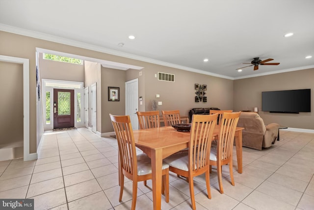 tiled dining space with ceiling fan and crown molding