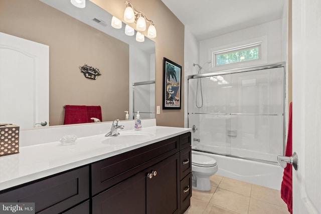 full bathroom with tile patterned flooring, vanity, bath / shower combo with glass door, and toilet