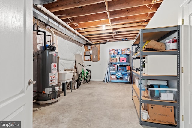 basement featuring electric panel, gas water heater, and sink