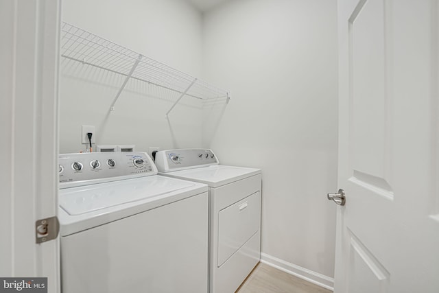 clothes washing area featuring washing machine and dryer and light wood-type flooring