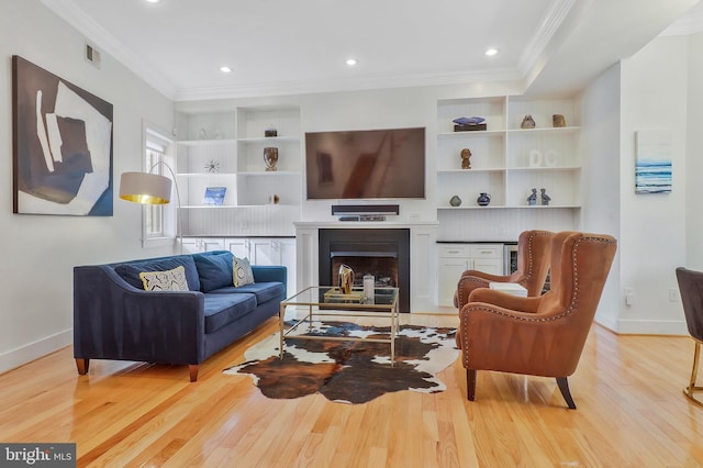 living room featuring built in shelves, light hardwood / wood-style floors, and ornamental molding