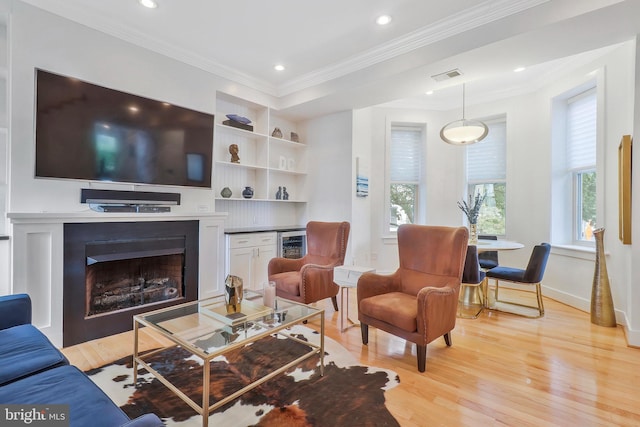 living room with wine cooler, crown molding, light hardwood / wood-style flooring, and built in features