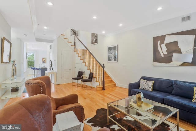 living room featuring wood-type flooring and crown molding