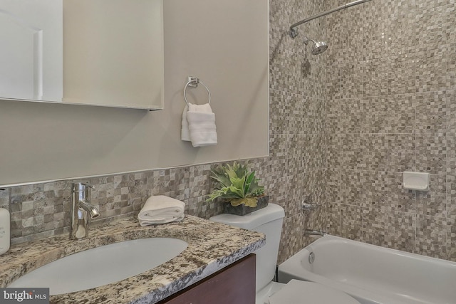 full bathroom with backsplash, vanity, tiled shower / bath combo, and toilet