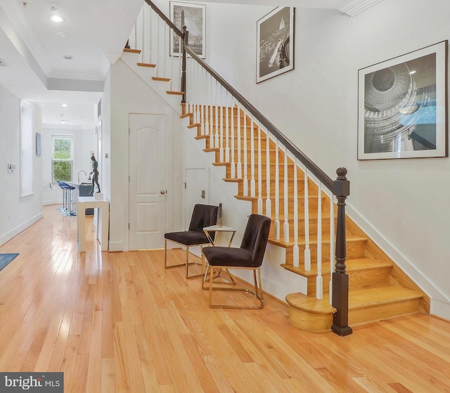 staircase with hardwood / wood-style flooring and crown molding