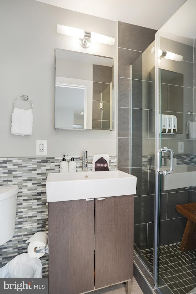 bathroom with an enclosed shower, vanity, toilet, and tile walls