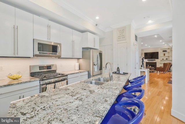 kitchen featuring a kitchen bar, appliances with stainless steel finishes, light stone counters, and sink