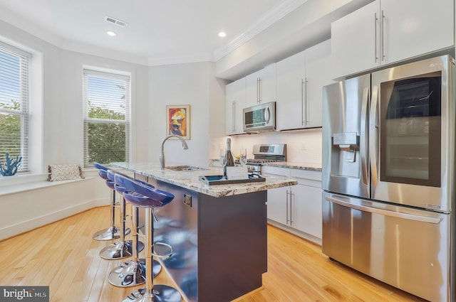 kitchen featuring white cabinetry, sink, stainless steel appliances, and a center island with sink