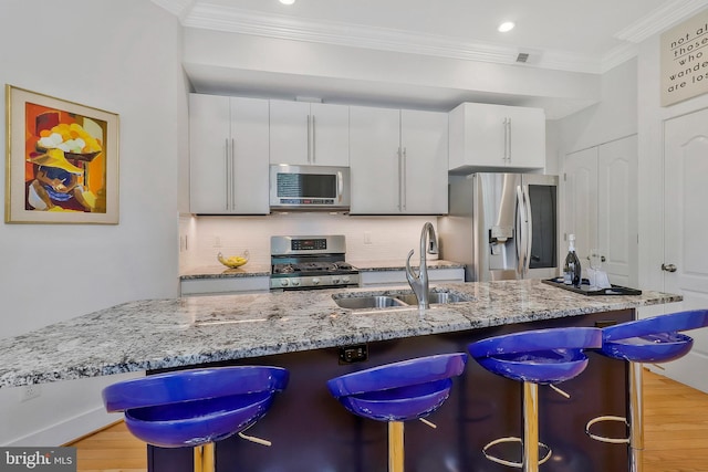 kitchen with backsplash, white cabinets, a kitchen breakfast bar, sink, and appliances with stainless steel finishes