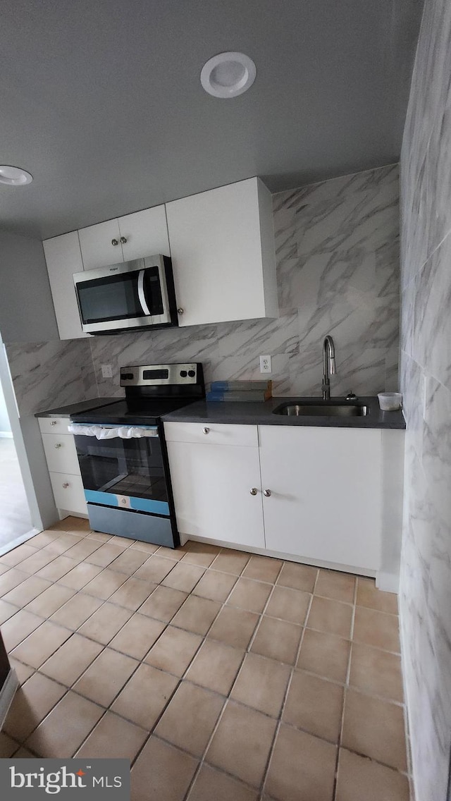 kitchen featuring appliances with stainless steel finishes, white cabinetry, sink, and light tile patterned flooring