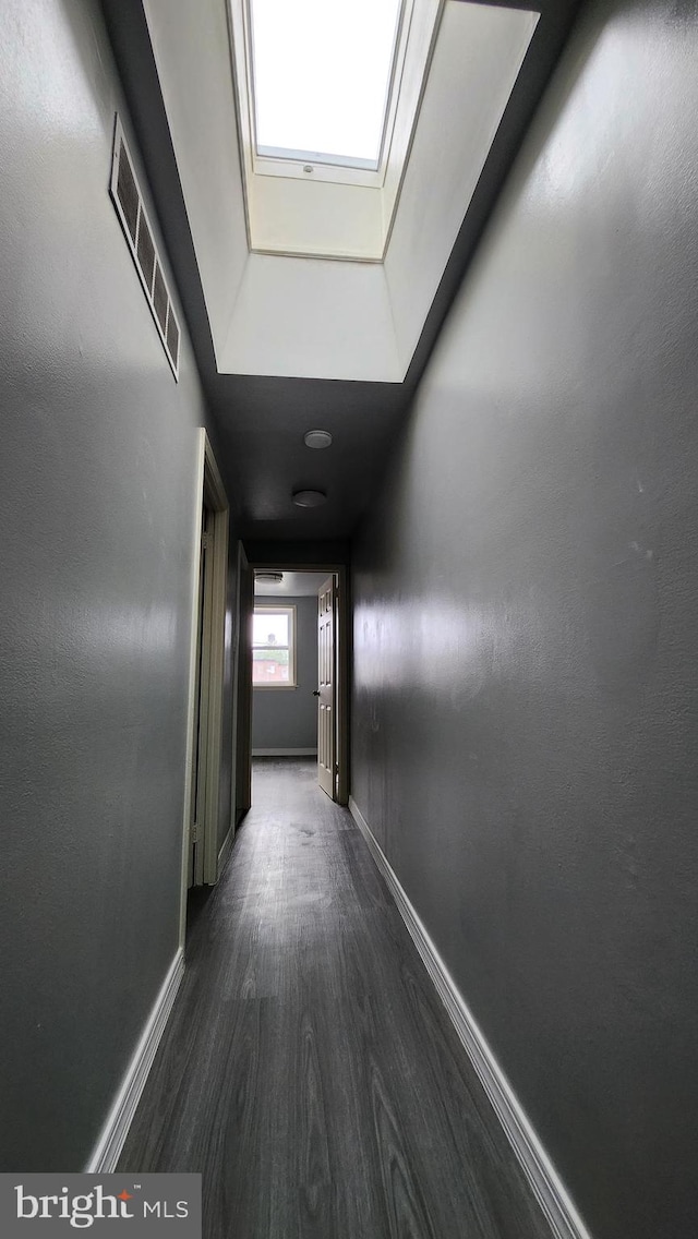 hallway featuring dark hardwood / wood-style floors and a skylight