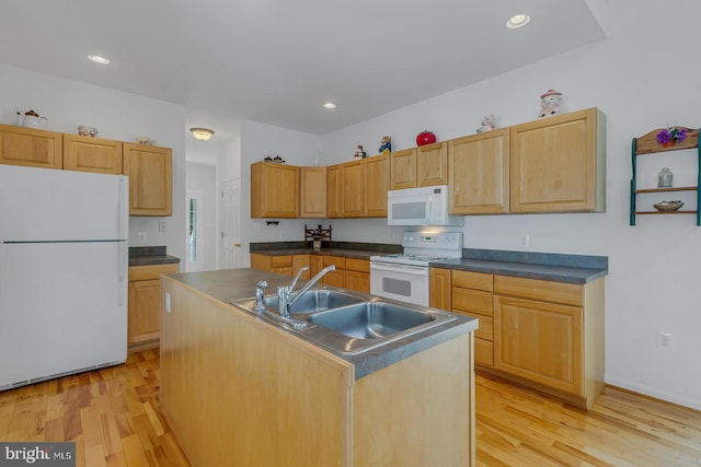 kitchen with light brown cabinets, white appliances, light wood-type flooring, sink, and a center island with sink