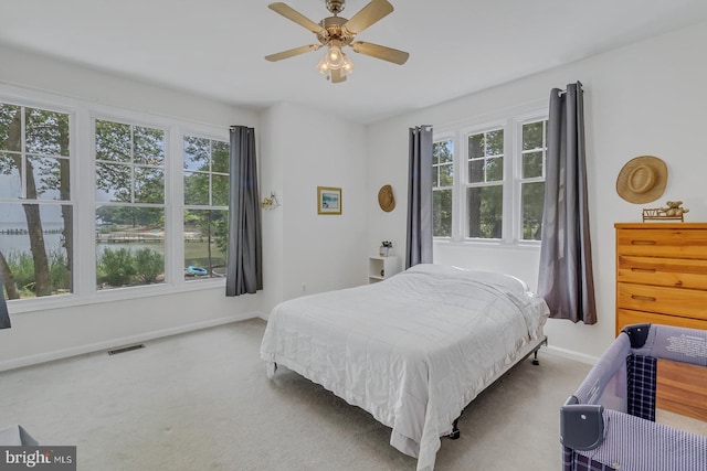 carpeted bedroom with multiple windows and ceiling fan