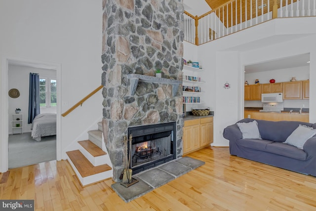 living room with a high ceiling, a fireplace, and light colored carpet