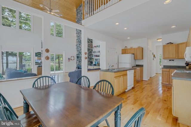 dining space featuring ceiling fan, light hardwood / wood-style floors, sink, and a high ceiling