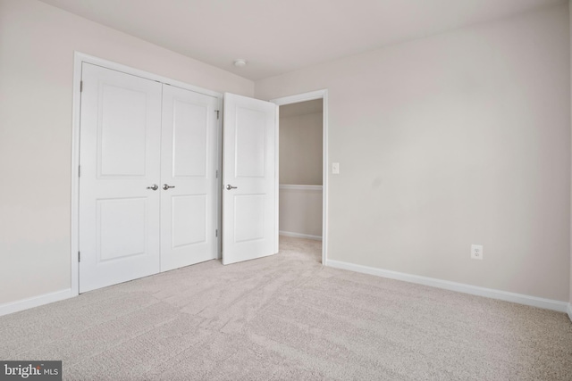 unfurnished bedroom featuring light carpet and a closet