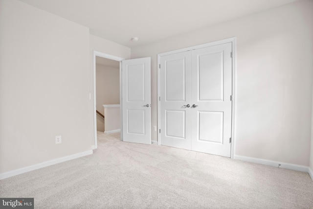 unfurnished bedroom featuring light colored carpet and a closet