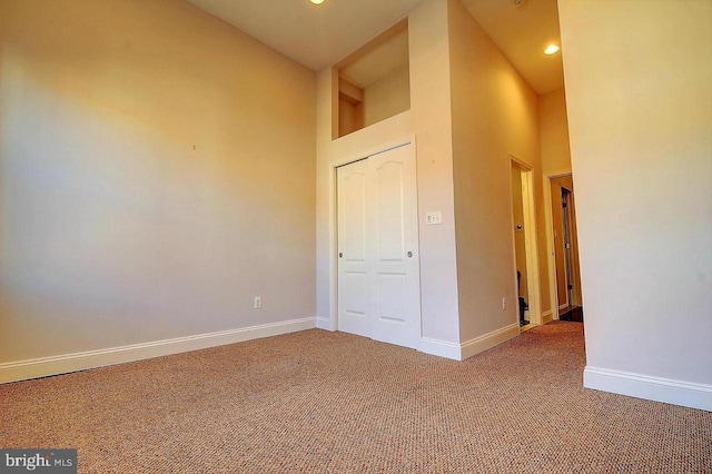 unfurnished bedroom featuring carpet floors and a towering ceiling