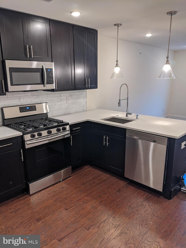 kitchen featuring hanging light fixtures, stainless steel appliances, dark hardwood / wood-style floors, and sink