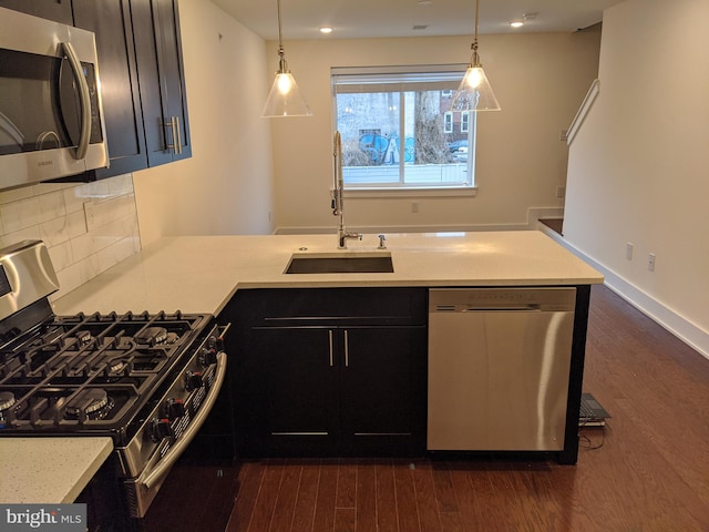 kitchen with backsplash, appliances with stainless steel finishes, sink, dark hardwood / wood-style floors, and pendant lighting