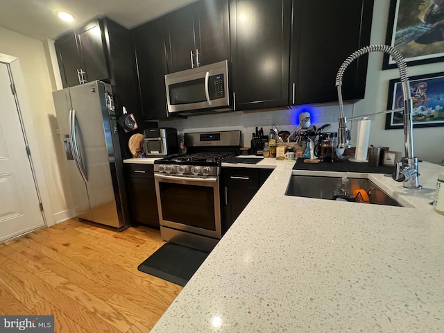 kitchen featuring appliances with stainless steel finishes, light stone counters, tasteful backsplash, and light hardwood / wood-style flooring