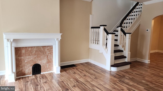 staircase with a tile fireplace and hardwood / wood-style flooring