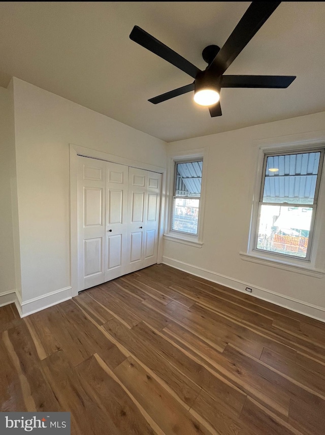 unfurnished bedroom featuring ceiling fan, dark hardwood / wood-style flooring, and a closet