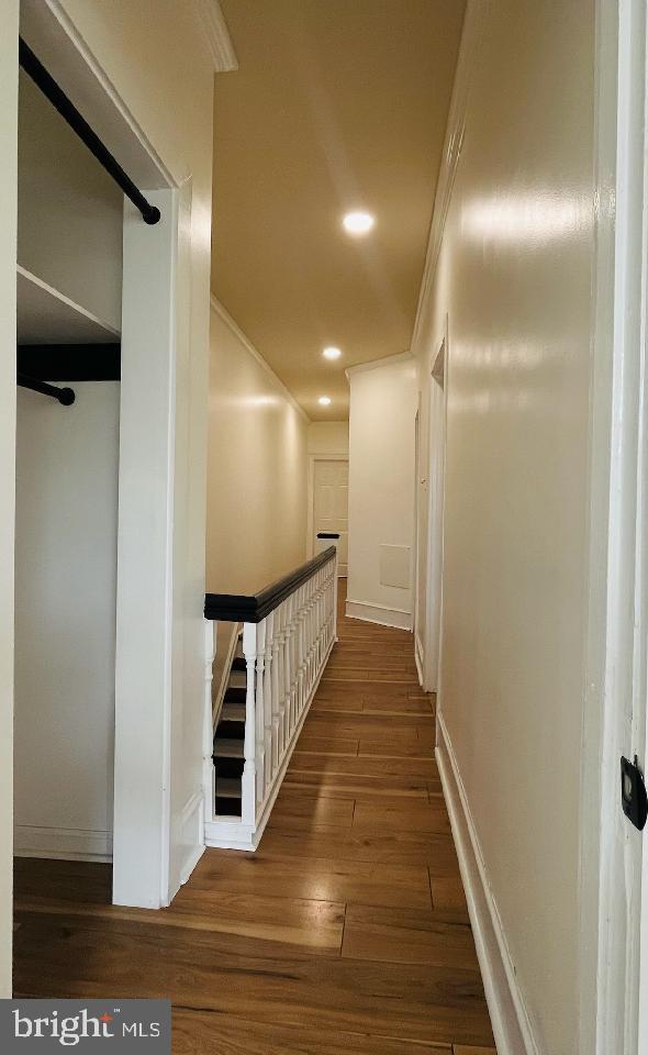 hallway with dark hardwood / wood-style flooring and ornamental molding