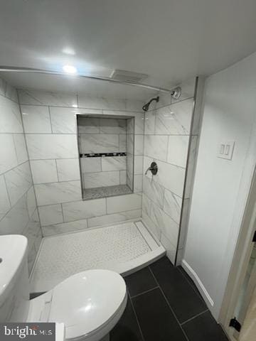 bathroom with toilet, tile patterned floors, and tiled shower