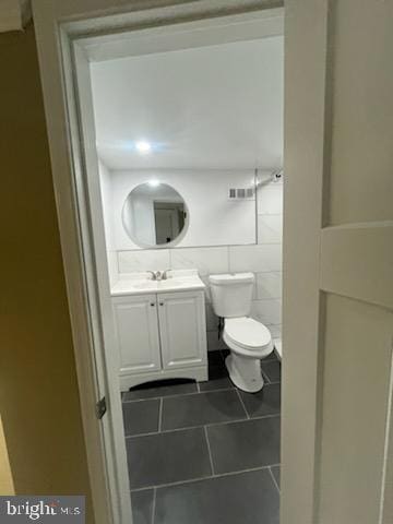 bathroom featuring tile patterned floors, tile walls, toilet, and vanity