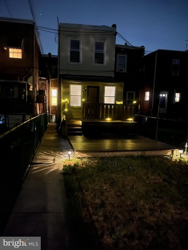 back house at night featuring a deck