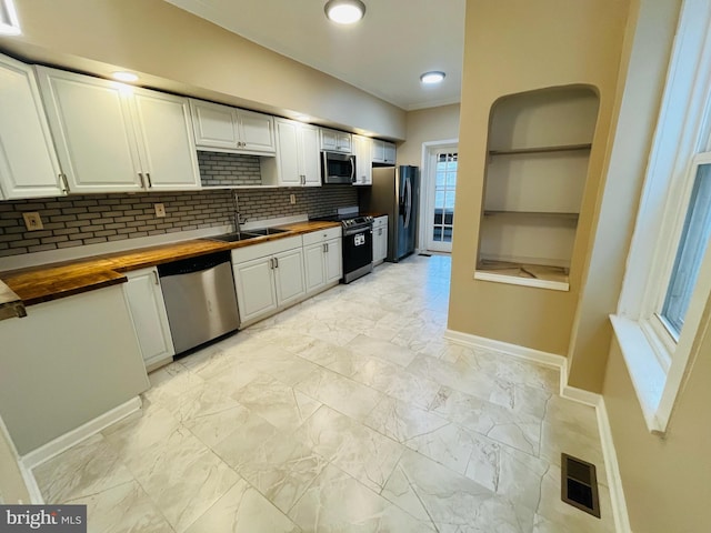 kitchen with sink, white cabinetry, stainless steel appliances, and wood counters