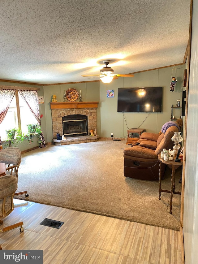 carpeted living room featuring a textured ceiling, ceiling fan, and a fireplace