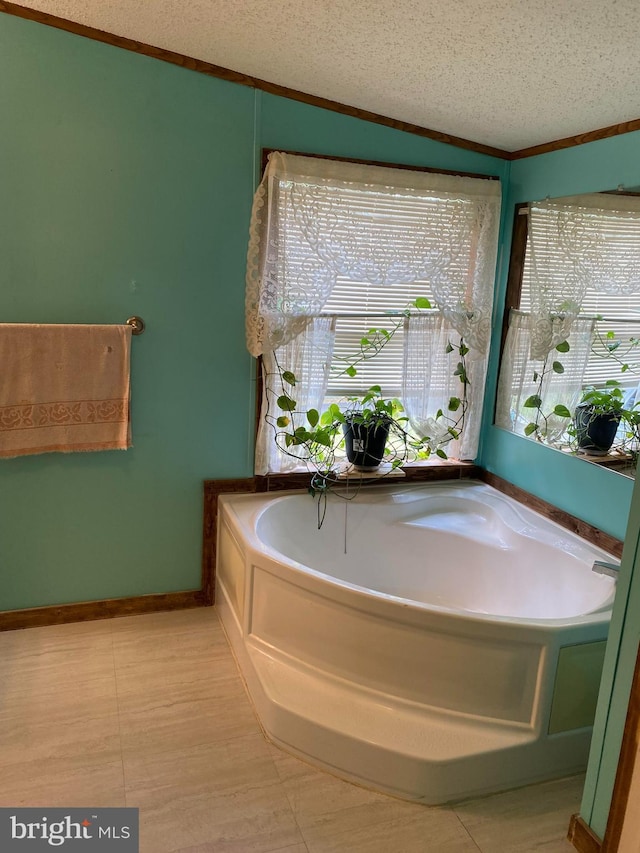 bathroom with ornamental molding, a textured ceiling, and a tub