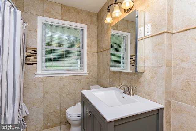 bathroom with vanity, toilet, and tile walls