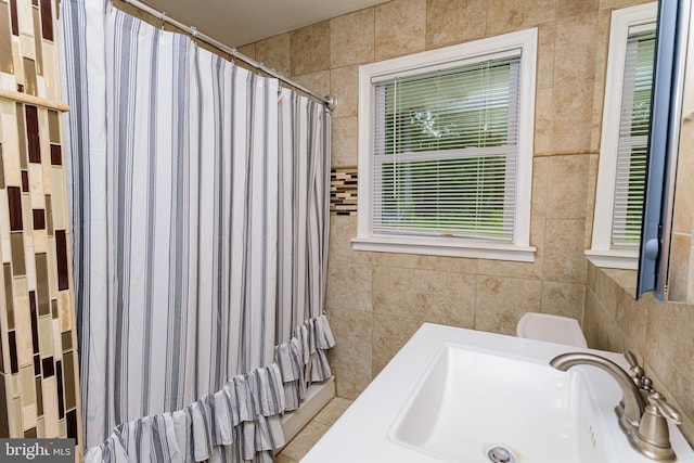 bathroom featuring curtained shower, sink, and tile walls