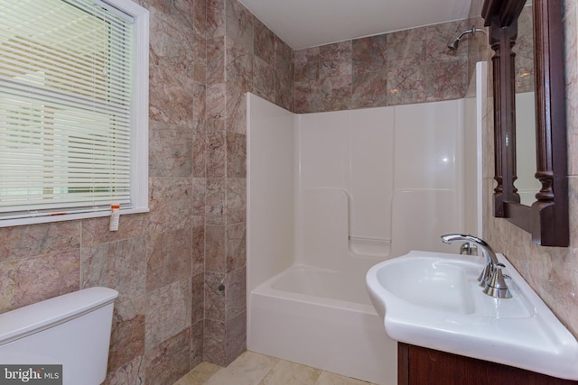 full bathroom with a healthy amount of sunlight, toilet,  shower combination, and tile walls