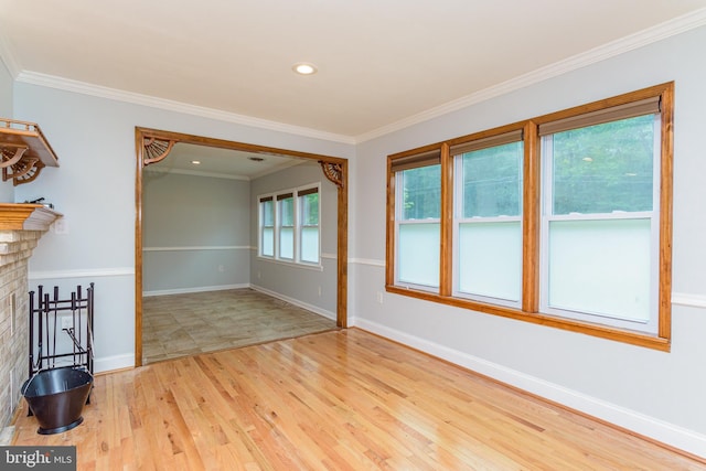 empty room featuring light hardwood / wood-style floors, a brick fireplace, and crown molding