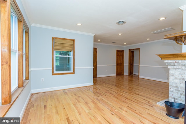 unfurnished living room featuring light wood-type flooring, ornamental molding, and a brick fireplace