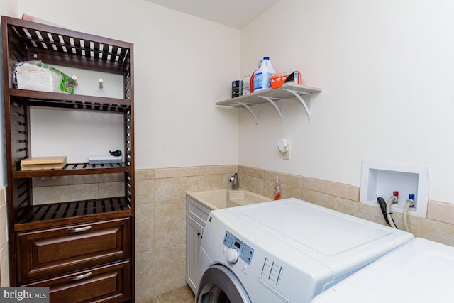 washroom with sink, cabinets, independent washer and dryer, light tile patterned floors, and tile walls