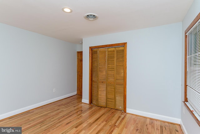 unfurnished bedroom with light hardwood / wood-style flooring and a closet