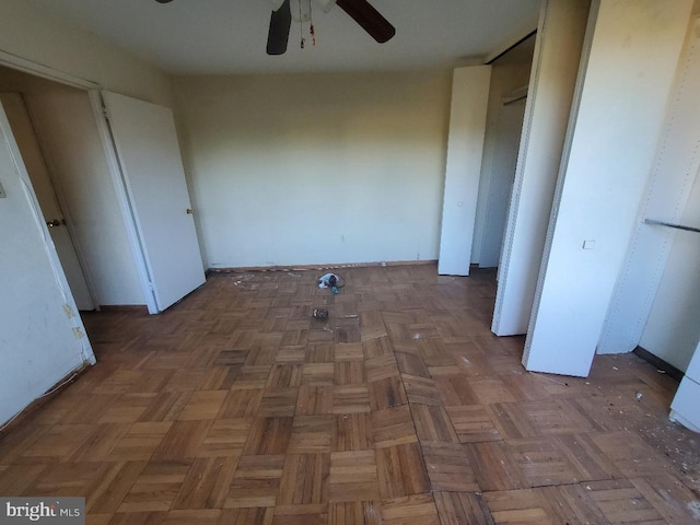 unfurnished bedroom with ceiling fan and dark parquet floors